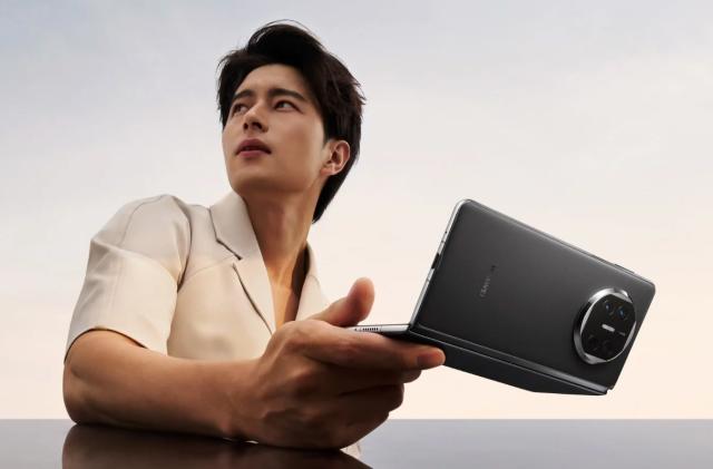 A male model posing with a black Huawei Mate X5 foldable phone.